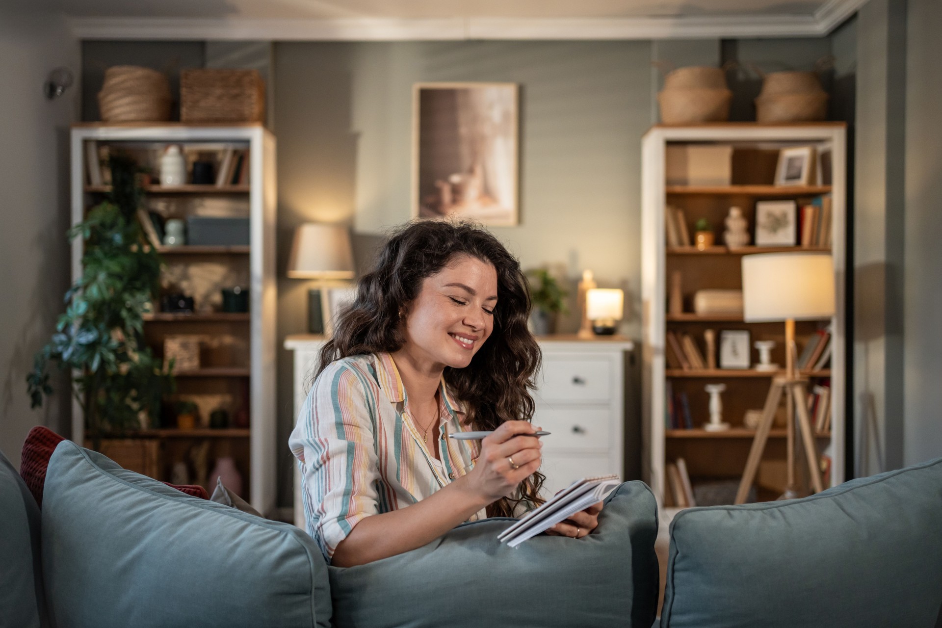Young woman smiling and writing on notebook at home